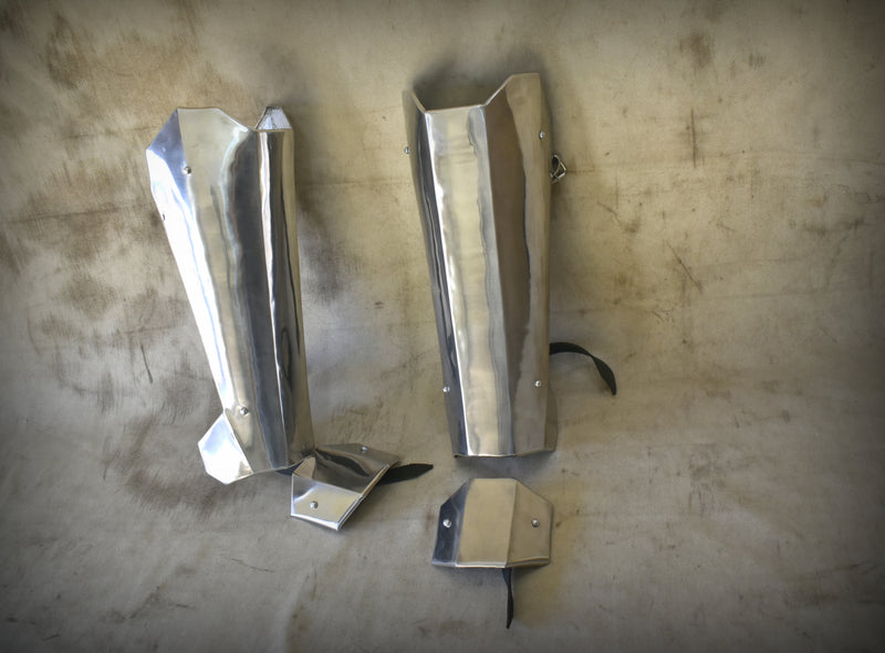 A front view of the Mandalorian shin armour, showcasing its sleek design and craftsmanship. The armour features a metallic finish