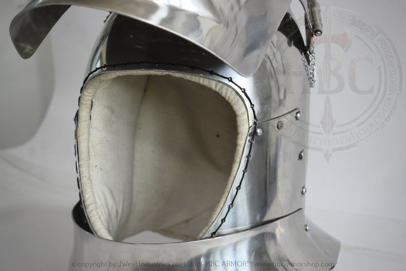 Close-up of a polished steel medieval helmet with a padded off-white interior lining and visible rivets, photographed against a light gray background.