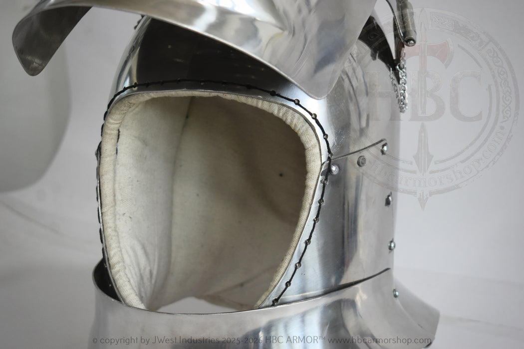 Close-up of a polished steel medieval helmet with a padded off-white interior lining and visible rivets, photographed against a light gray background.