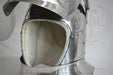 Close-up of a polished steel medieval helmet with a padded off-white interior lining and visible rivets, photographed against a light gray background.