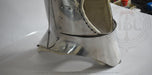 A close-up of a metallic silver medieval-style boot or boot cover with rivets and a chain detail, photographed on a white surface.