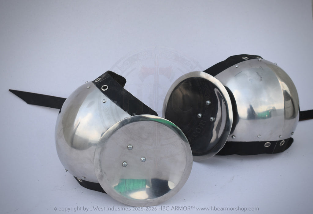 Two polished steel medieval round helmets with black padded undercaps and straps, displayed on a light gray background.