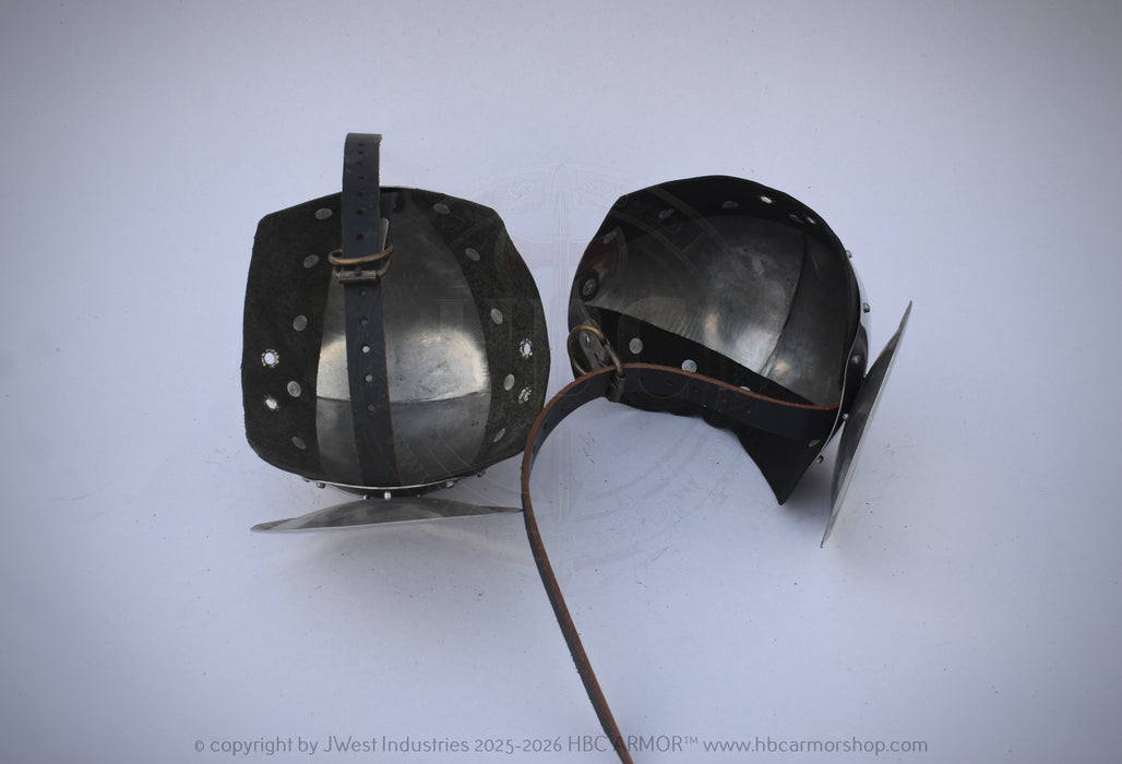 A pair of medieval-style steel helmet visors with leather straps, displayed on a light gray background.