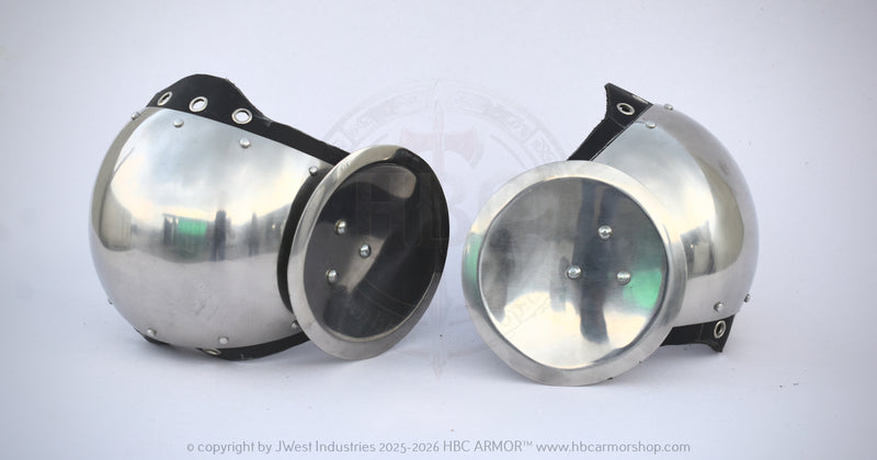 Two polished steel glomerin armor helmets with black leather straps and rivets, displayed side-by-side on a white background.