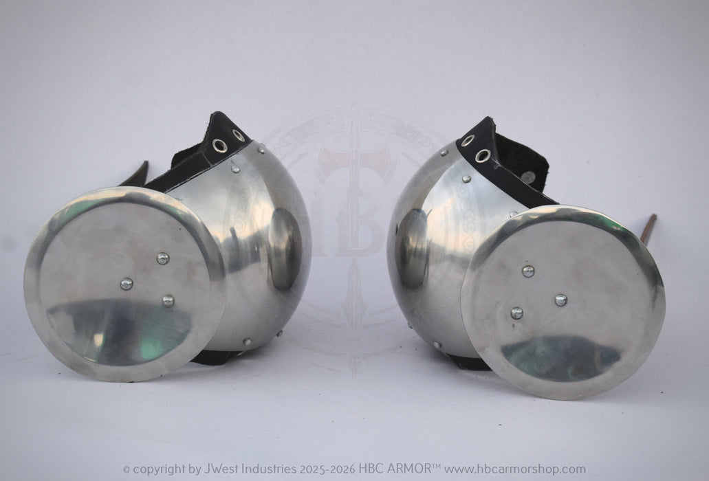 A pair of vintage-style metal arm guards with circular silver steel plates and black adjustable straps, displayed on a light gray background.