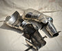A pair of medieval steel plate armor leg guards and shin guards displayed on a light beige fabric backdrop.