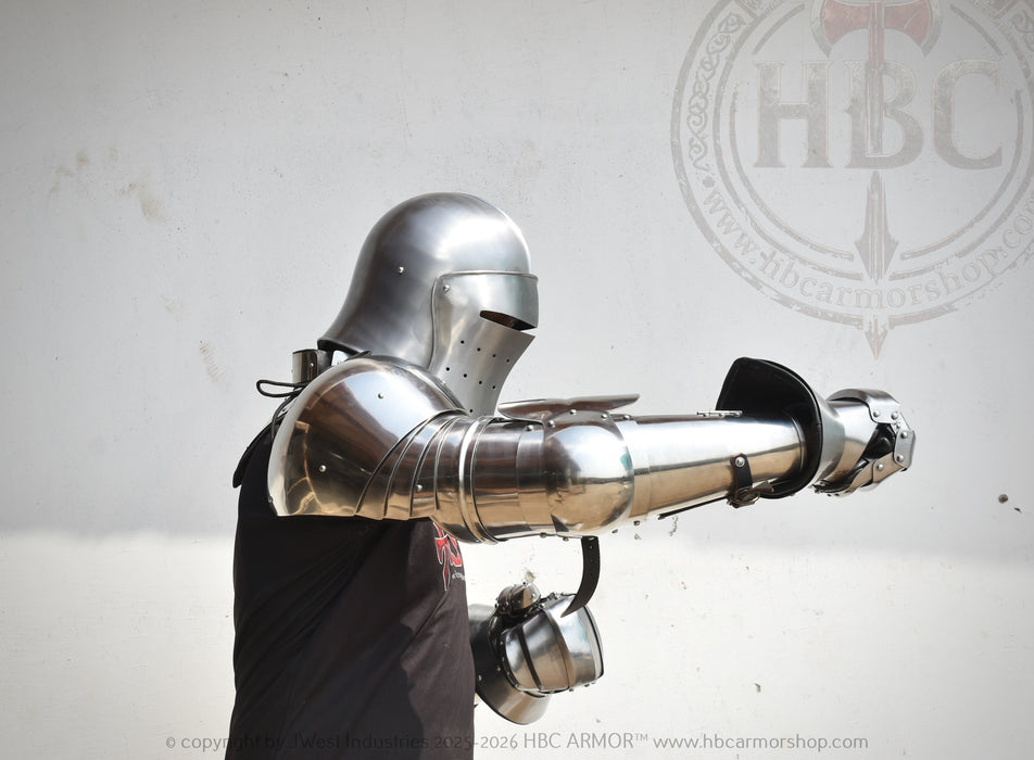 A person wearing full medieval-style steel plate armor with a helmet, breastplate, gauntlets, and a chainmail coif, posed against a plain light background. A faint HBC Armor logo watermark appears behind the subject.
