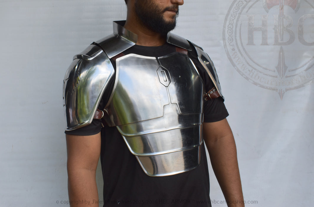 A man wearing a polished steel breastplate armor piece over a black t-shirt, shown from the chest up against a white backdrop with a faint logo.