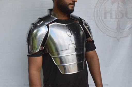 A man wearing a polished steel breastplate armor piece over a black t-shirt, shown from the chest up against a white backdrop with a faint logo.