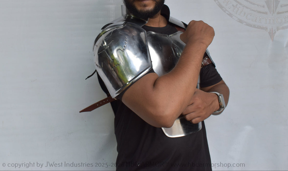 A man wearing a shiny metallic steel replica of a medieval plate armor shoulder guard, shown against a white backdrop with a faint logo watermark.