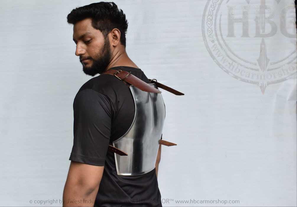 A man shown from the back wearing a metallic silver and black body armor vest with brown leather straps, standing against a white branded backdrop.